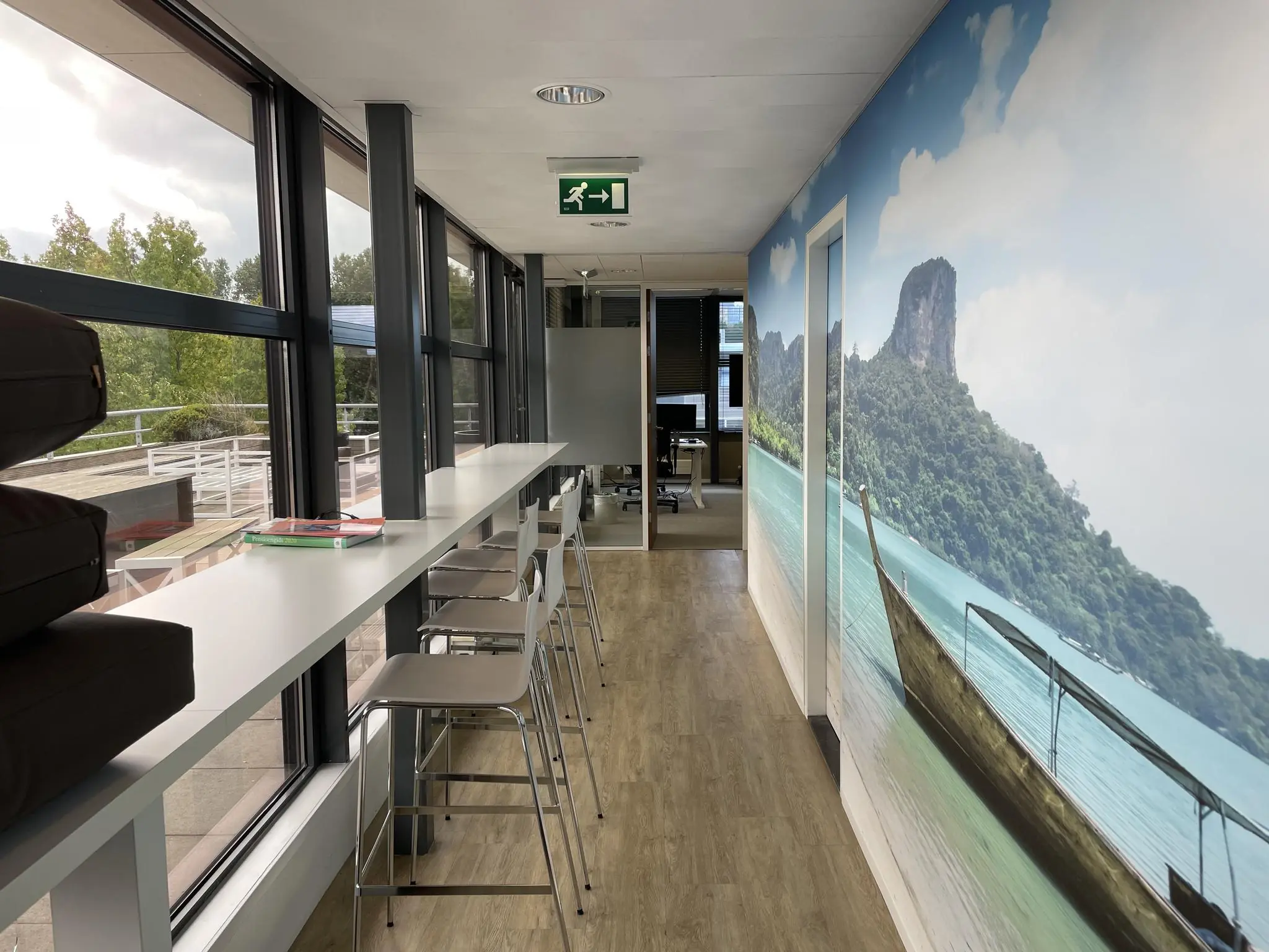 Moderne kantoorruimte aan de Jan Leentvaarlaan met een hoge tafel bij het raam en een wand met tropische fotoprint.